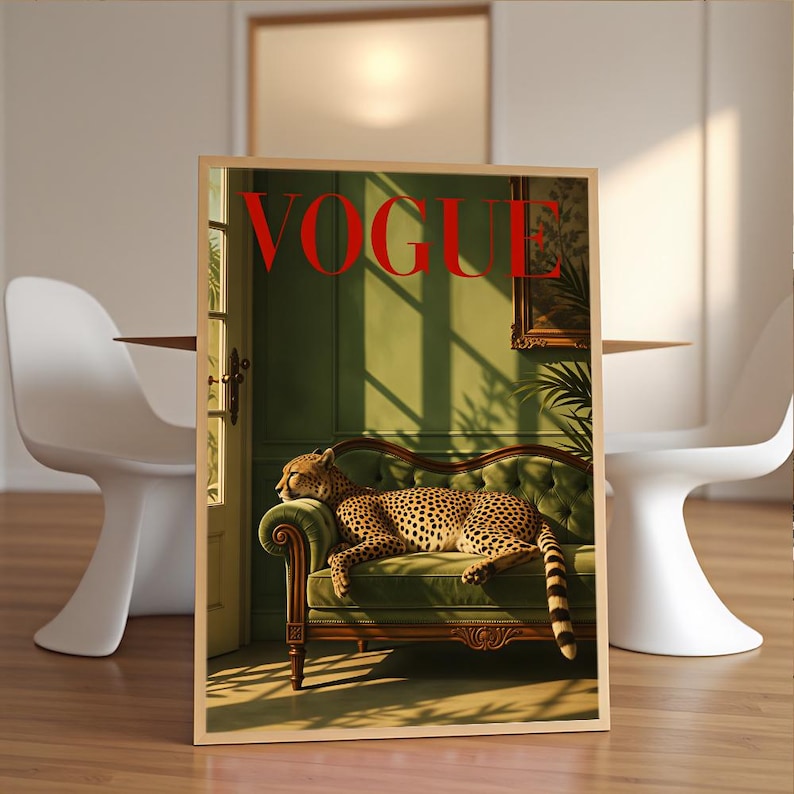 May include: A rectangular wall art print featuring a cheetah resting on a green tufted sofa inside a room with green walls and a doorway. The word VOGUE is printed in large red capital letters at the top of the image, which is framed in light wood.