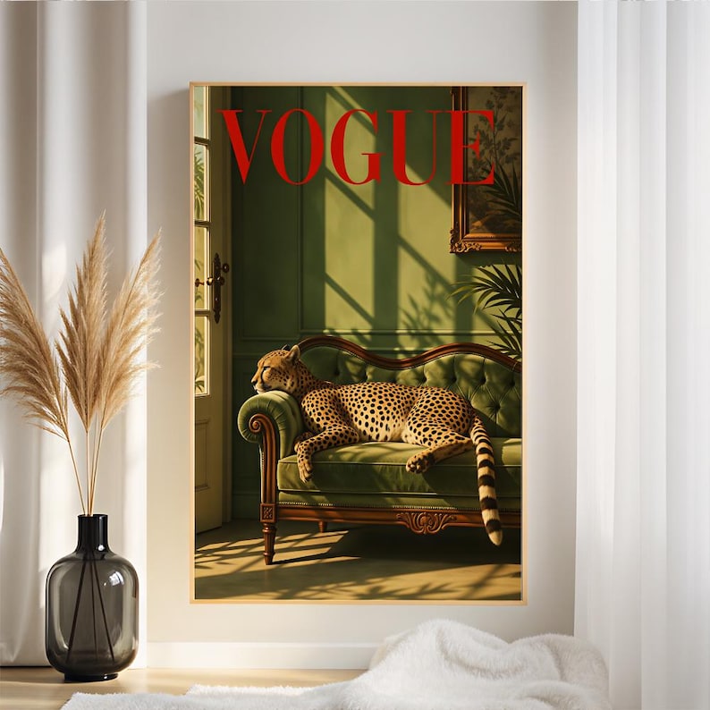 May include: A rectangular wall art print featuring a cheetah resting on a green tufted sofa. The word VOGUE is printed in large red capital letters at the top. The scene depicts a room with green walls, sunlight casting shadows, and a framed picture.