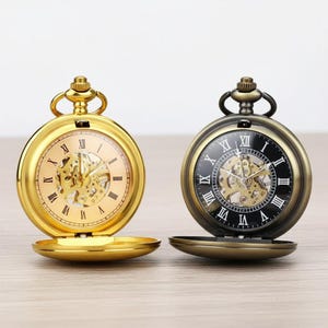 Puede incluir: Una taza de cerámica blanca con asa negra y el texto "But First, Coffee" en negrita negra. La taza se encuentra sobre un fondo borroso, sugiriendo un ambiente acogedor.