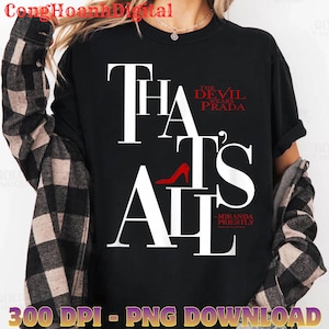 Puede incluir: Camiseta negra con el texto "THAT'S ALL" en letras blancas grandes, con "THE DEVIL WEARS PRADA" en rojo arriba. Un gráfico de zapato de tacón alto rojo está en el centro. La camiseta también tiene el texto "-MIRANDA PRIESTLY".