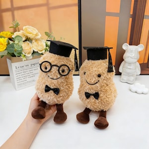 May include: A white ceramic mug with a black handle and the text "But First, Coffee" in a black, bold font. The mug is sitting on a wooden surface. The mug is approximately 4 inches tall.