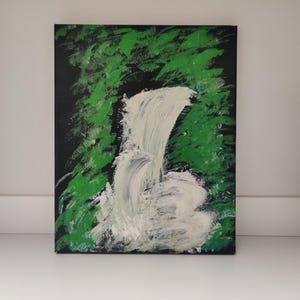 Puede incluir: Pintura acrílica sobre lienzo que representa una cascada. La obra presenta una cascada blanca sobre un fondo negro. Las pinceladas verdes representan el follaje, creando un contraste de colores y texturas. La pintura está montada sobre una superficie blanca.