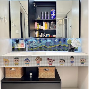 Puede incluir: Un tocador de baño moderno con encimera blanca, salpicadero de mosaico y borde decorativo con figuras pixeladas. El tocador incluye un lavabo, cestas de almacenamiento y un armario con espejo lleno de artículos de aseo.