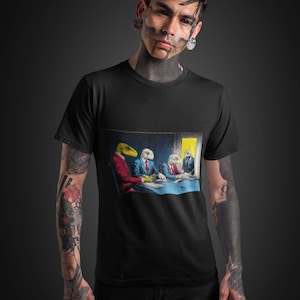May include: Black t-shirt featuring a surreal illustration of reptilian figures in suits seated around a table. The figures have reptile heads and are wearing suits. The background is a dark room with a yellow light.
