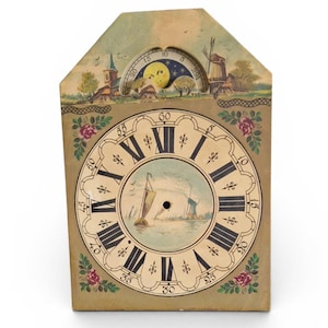 Puede incluir: Una esfera de reloj vintage con una escena de paisaje pintada. El reloj presenta números romanos, una imagen náutica central y un borde floral decorativo. La sección superior representa un indicador de fase lunar y un paisaje rural.