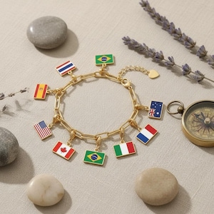 May include: A gold-toned chain link bracelet featuring multiple rectangular enamel charms, each displaying a different national flag, including the United States, Canada, Brazil, Italy, France, Australia, Spain, Thailand, and a green-yellow-blue flag.
