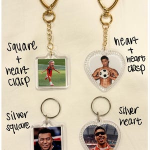 May include: Four acrylic keychains featuring athlete photos. Top left: square shape with gold heart clasp. Top right: heart shape with gold heart clasp. Bottom left: square shape with silver ring. Bottom right: heart shape with silver ring.