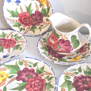 May include: A white ceramic mug with a black handle and the text "But First, Coffee" in a black, handwritten-style font. The mug is on a white surface.