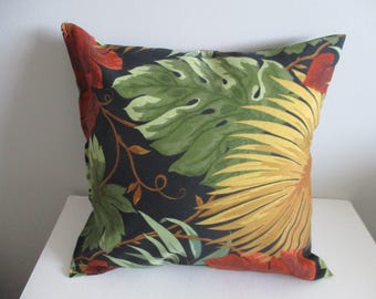 May include: Square decorative pillow with a tropical floral pattern. The pillow features large green leaves, yellow flowers, and red accents on a dark background. The pillow is square and appears to be made of fabric.