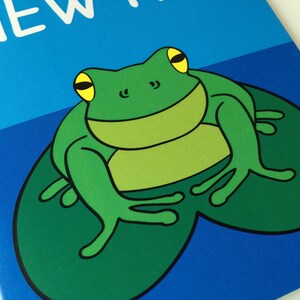May include: A cartoon illustration of a green frog with yellow eyes sitting on a lily pad. The frog is set against a blue background with the word "NEW" in white text.