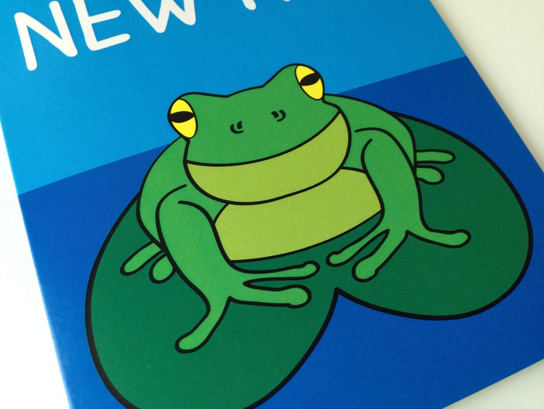 May include: A cartoon illustration of a green frog with yellow eyes sitting on a lily pad. The frog is set against a blue background with the word "NEW" in white text.
