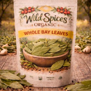 May include: A package of "Wild Spices Organic Whole Bay Leaves" is displayed on a wooden surface. The bag features a yellow banner with the product name and a wooden bowl filled with green bay leaves. The background is a blurred outdoor scene.