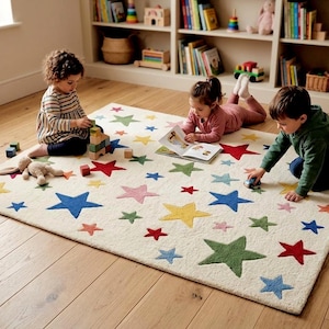 May include: A rectangular area rug with an off-white base featuring a scattered pattern of multi-colored stars in shades of red, blue, green, yellow, and pink. The rug has a textured surface and is positioned on a wooden floor.