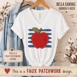May include: A white V-neck t-shirt featuring a red apple graphic with a green leaf, layered over horizontal blue distressed stripes. The design mimics a faux patchwork style. The shirt is displayed on a wooden hanger with a denim shirt.