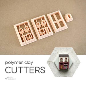 Puede incluir: Un conjunto de cortadores de arcilla polimérica rosa claro con forma de fachadas de edificios. Los cortadores son rectangulares con diseños detallados de ventanas y puertas. La imagen también incluye un edificio en miniatura terminado y el texto "polymer clay CUTTERS".