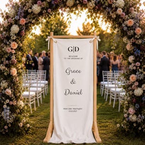 Rustic wooden wedding welcome stand with hanging canvas banner, floral arch ceremony entrance sign for outdoor weddings