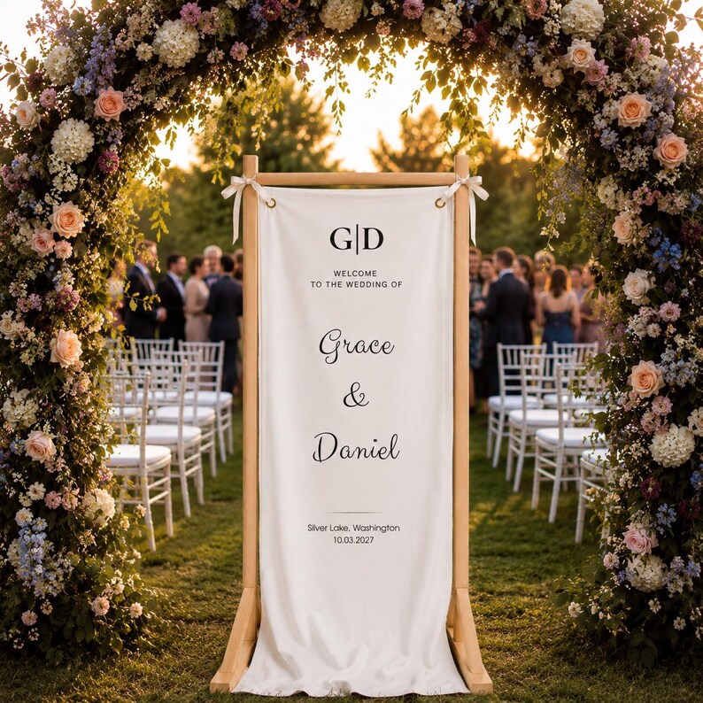 Rustic wooden wedding welcome stand with hanging canvas banner, floral arch ceremony entrance sign for outdoor weddings
