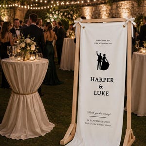 Romantic outdoor wedding decor with personalized wooden welcome stand, fabric banner and floral ceremony entrance
