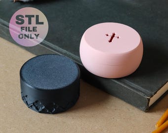 May include: Two small, round containers. One is black with a textured top and a floral pattern on the side. The other is light pink with a cross-shaped cutout on top. The image includes the text "STL FILE ONLY".