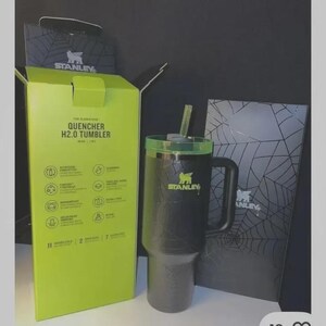 May include: Black Stanley Quencher H2.0 tumbler with a green lid and straw. The tumbler has a handle and the Stanley logo. The box is lime green and black with the text "QUENCHER H2.0 TUMBLER".
