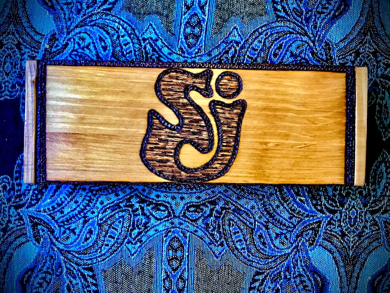May include: A wooden sign with a brown and black "SJ" logo in the center. The sign has a dark brown border.