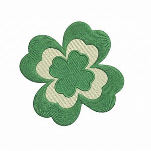 May include: Embroidered shamrock design in shades of green and off-white. The clover has three layers of petals, with a detailed stitch pattern. The design is set against a white background.