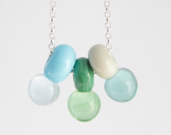 May include: A silver chain necklace with a cluster of pastel blue, green, and white glass beads.