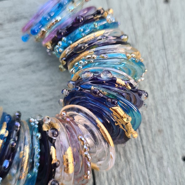 Handgefertigte Scheibenperlen aus Muranoglas in den Farben Lila, Flieder, Türkis und Klar mit 24-karätigem Blattgold und silberreichen Glasdetails