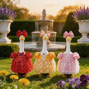 May include: Three goose figurines dressed in colorful dresses and hats, standing in a garden. The geese wear red, yellow, and pink dresses with butterfly patterns, each with a matching hat and bow. A fountain and flower pots are in the background.