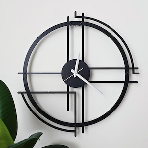 May include: A black metal wall clock featuring a circular frame with intersecting horizontal and vertical lines. The center consists of a solid black circular dial with three white clock hands. The design incorporates open geometric segments.