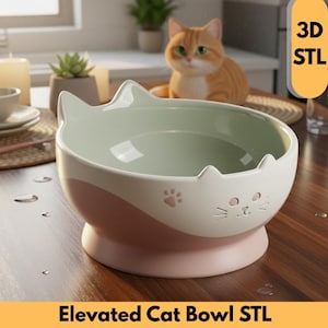 May include: A two-tone cat bowl with a pink base and a white top with a mint green interior. The bowl has a cat face design with ears and a paw print. The text "Elevated Cat Bowl STL" is at the bottom.