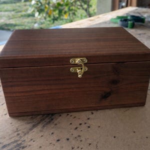 Puede incluir: Un letrero de madera rústica con la frase "Welcome to our home" en letras blancas. El letrero presenta un acabado envejecido y un diseño sencillo y acogedor, perfecto para un porche o entrada.