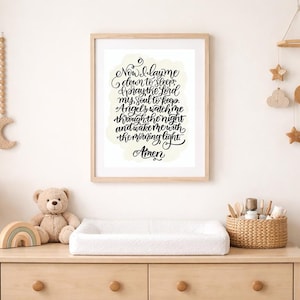Puede incluir: Una impresión enmarcada con el texto "Now I lay me down to sleep, I pray the Lord my soul to keep. Angels watch me through the night and wake me with the morning light. Amen." se muestra sobre una mesa para cambiar pañales en un cuarto de niños.