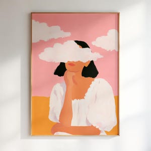 Puede incluir: Una impresión artística enmarcada que presenta a una mujer con cabello negro y una nube blanca que cubre sus ojos. La obra de arte tiene un fondo rosa y naranja, y la mujer lleva un vestido blanco. El arte está en un marco de madera.