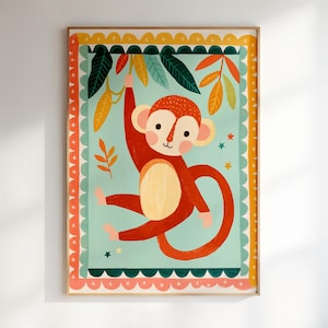 Op de afbeelding: Een ingelijste kunstdruk met een cartoon aap die aan een tak hangt. De aap is rood met een beige buik en gezicht. De achtergrond is lichtblauw met groene en gele bladeren. De lijst heeft een decoratieve rand met roze, oranje en gele accenten.