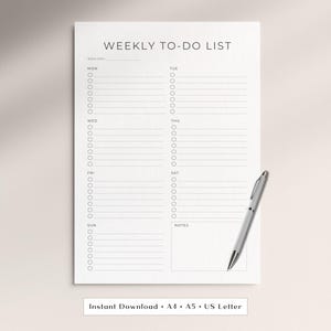 Peut inclure: Une page de planification hebdomadaire blanche avec du texte et des lignes noirs. L'en-tête indique WEEKLY TO-DO LIST et comprend des sections pour chaque jour de la semaine du lundi au dimanche, avec une zone de notes en bas. Un stylo argenté est posé.
