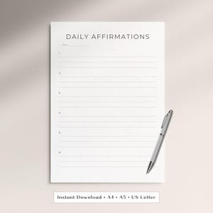 Könnte beinhalten: Ein weißes Blatt Papier mit der Überschrift DAILY AFFIRMATIONS in schwarzer Schrift, einer Datumszeile und sechs nummerierten Zeilen zum Schreiben. Ein silberner Kugelschreiber liegt auf der unteren rechten Ecke des Papiers vor einem neutralen Hintergrund.