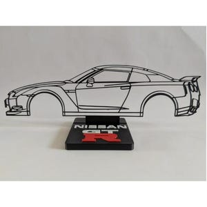 Op de afbeelding: Een zwart draadmodel silhouet van een Nissan GT-R sportwagen gemonteerd op een rechthoekige zwarte voet. De voet bevat de witte tekst NISSAN en een opvallend rood R-logo. De structuur is een zijprofielweergave van de carrosserie van de auto.