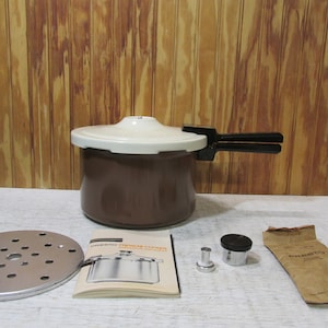 May include: A brown Presto pressure cooker with a white lid and a black handle. The cooker is accompanied by a metal trivet, a manual, two pressure regulator weights, and a brown paper bag with the Presto logo.