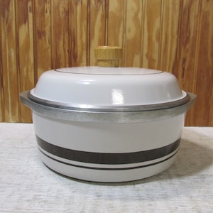 May include: White enamel Dutch oven with a black and white striped design and a wooden knob on the lid.