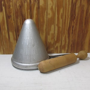 May include: A white ceramic mug with a black handle and the text "But First, Coffee" in a bold, black font. The mug is filled with a dark liquid, likely coffee, and sits on a light-colored surface.