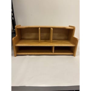 May include: A light brown wooden desktop organizer featuring two tiers. The top tier is divided into two sections by a central vertical divider, while the bottom tier is divided into two unequal sections by a smaller vertical divider on the right side.