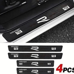 Może przedstawiać: Czarne ochraniacze progów drzwi z włókna węglowego z białymi logo "Volkswagen R". Zestaw zawiera cztery elementy, zaprojektowane w celu ochrony progów drzwi przed zarysowaniami i zużyciem. Widoczny tekst "4 PCS".