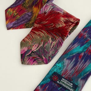 May include: Three colorful neckties with abstract patterns. One tie features a purple, red, and yellow design. Another has a red and pink pattern. The third tie is teal and purple with a label that reads "Molecular Expressions By Stonehenge".