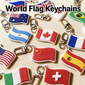 Puede incluir: Llaveros con banderas del mundo, como la de Estados Unidos, Canadá y China. Cada llavero tiene un cierre plateado. El texto "World Flag Keychains" se muestra en la parte superior de la imagen.