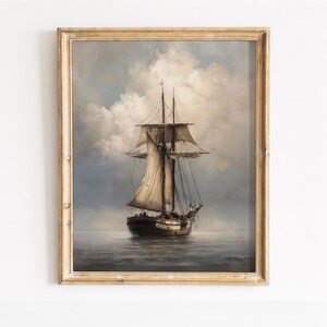 May include: A framed vintage painting of a tall ship sailing on the ocean. The artwork features a detailed depiction of the ship with billowing sails against a cloudy sky. The frame is a light gold colour.