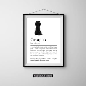 May include: Framed print with a black Cavapoo dog illustration. The print includes the breed's name, pronunciation, and a description of its characteristics. The bottom of the print has the text "Pippa & Co Studio".