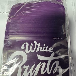 May include: A sealed package with a purple background and the words "White Runtz" in white script. The package is in a clear plastic bag, and the word "RESEALABLE" is visible.