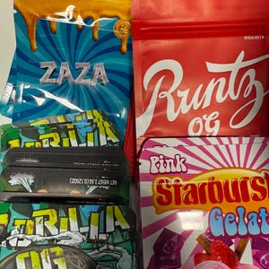 May include: Assortment of colorful resealable bags and boxes. The bags feature the text "ZAZA" on a blue background, "Runtz OG" on a red bag, and "Gorilla OG" on a green bag. A box displays "Pink Starburst Gelato".