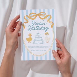 May include: A birthday invitation with a light blue striped background. The invitation features the text "Olivia's Birthday" in a script font, along with illustrations of ducks and a cake. The invitation is held by two hands.